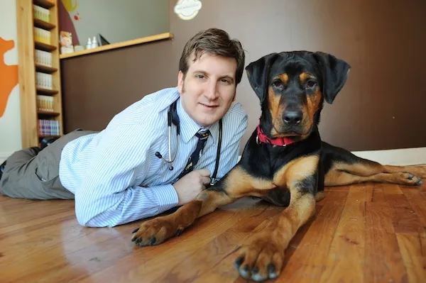 Dr. Timothy Mann lying on a wood floor beside a Rottweiler